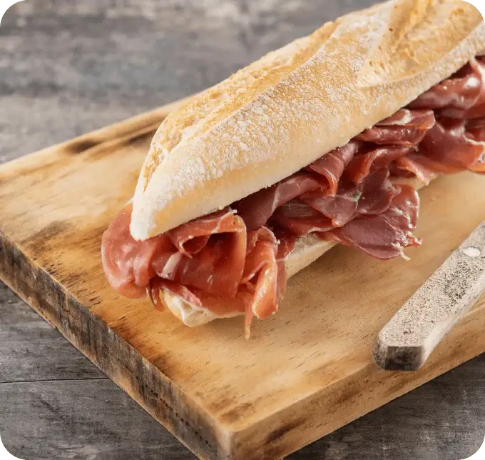 Traditionelles spanisches Bocadillo mit Jamón Ibérico auf Holzbrett serviert.