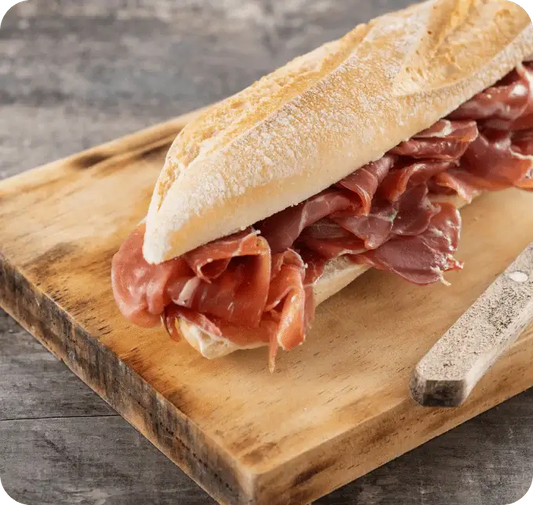 Traditionelles spanisches Bocadillo mit Jamón Ibérico auf Holzbrett serviert.