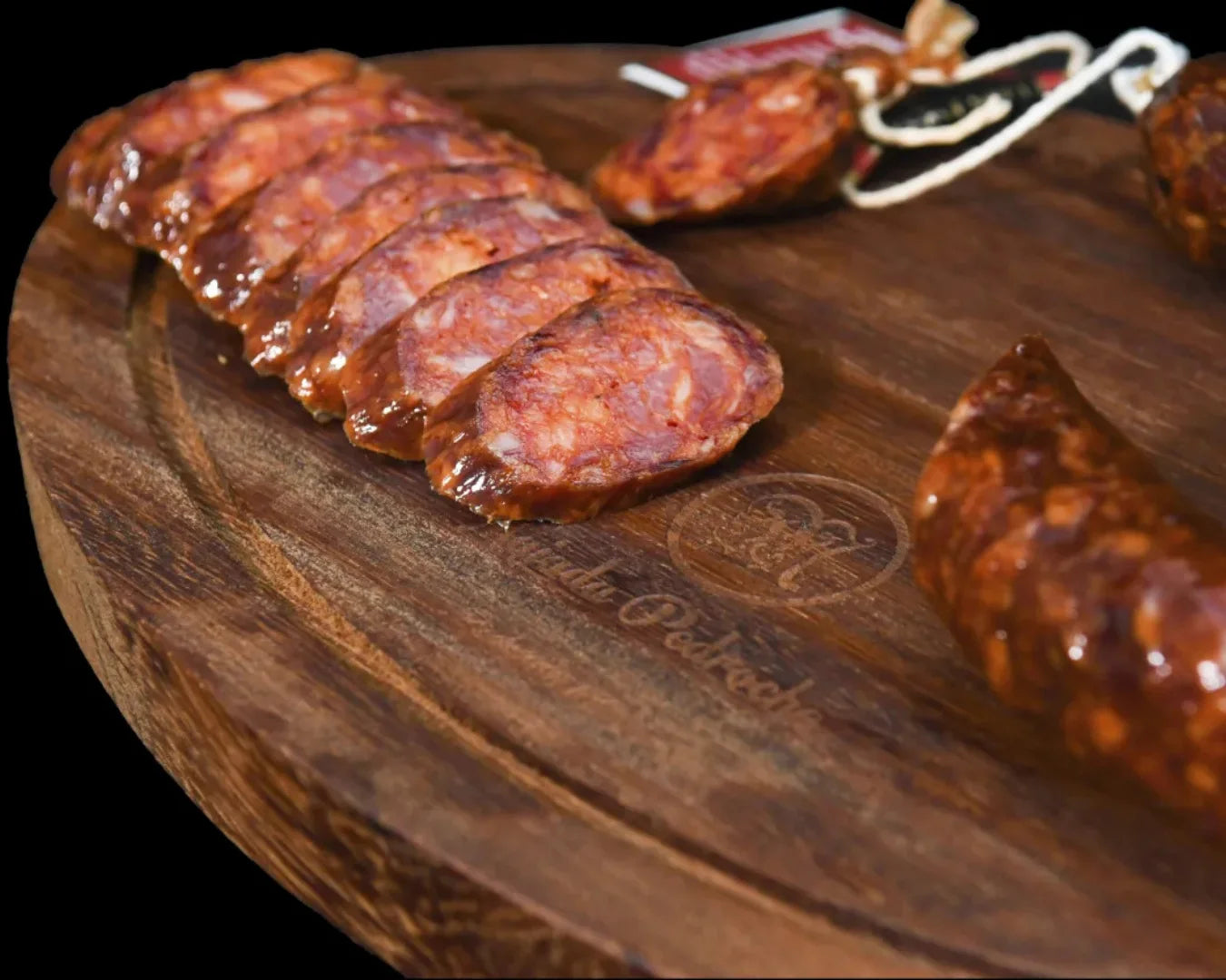 Aufgeschnittener Chorizo Ibérico de Bellota von Majada Pedroche auf einem Holzbrett, leuchtend rote Scheiben mit charakteristischer Fettmarmorierung aus dem Valle de Los Pedroches, Córdoba