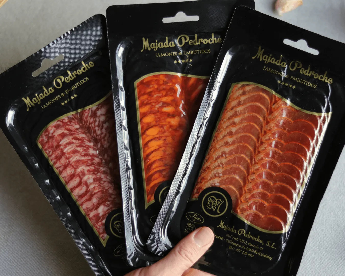 Drei vakuumverpackte spanische Wurstaufschnitte von Majada Pedroche – Salchichón, Chorizo und Lomo – hochwertig präsentiert in schwarzen Verpackungen; spanische Delikatessen für Tapas, Gourmet-Platten und Feinkost.