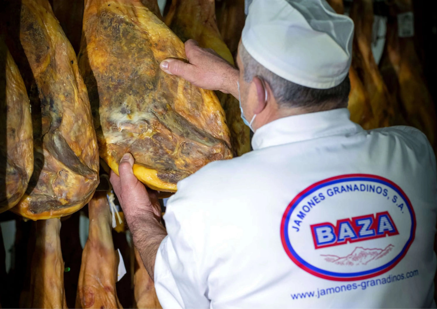Facharbeiter von Jamones Granadinos Baza kontrolliert sorgfältig die Reifung der Schinken im Trocknungsraum.