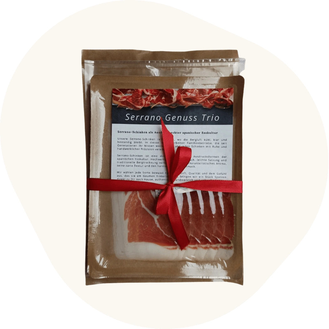 Geschenkset Serrano Genuss Trio im Kraftpapierbeutel: fein geschnittener Serrano-Schinken im Blister, zusammen mit Produktkarte und rotem Geschenkband.