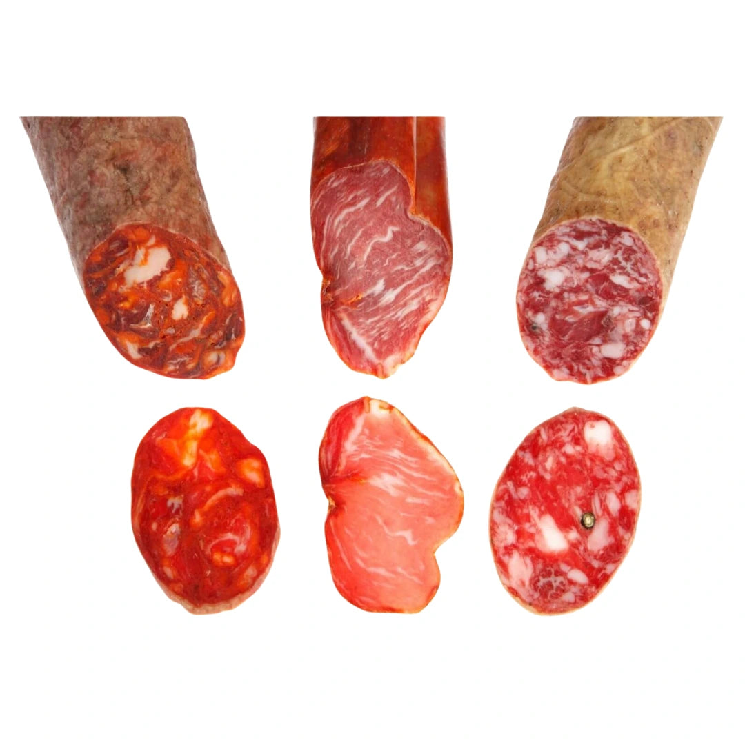 Anschnitt und Scheiben von Chorizo Ibérico, Lomo Ibérico und Salchichón Ibérico nebeneinander, mit sichtbarer Fettmarmorierung