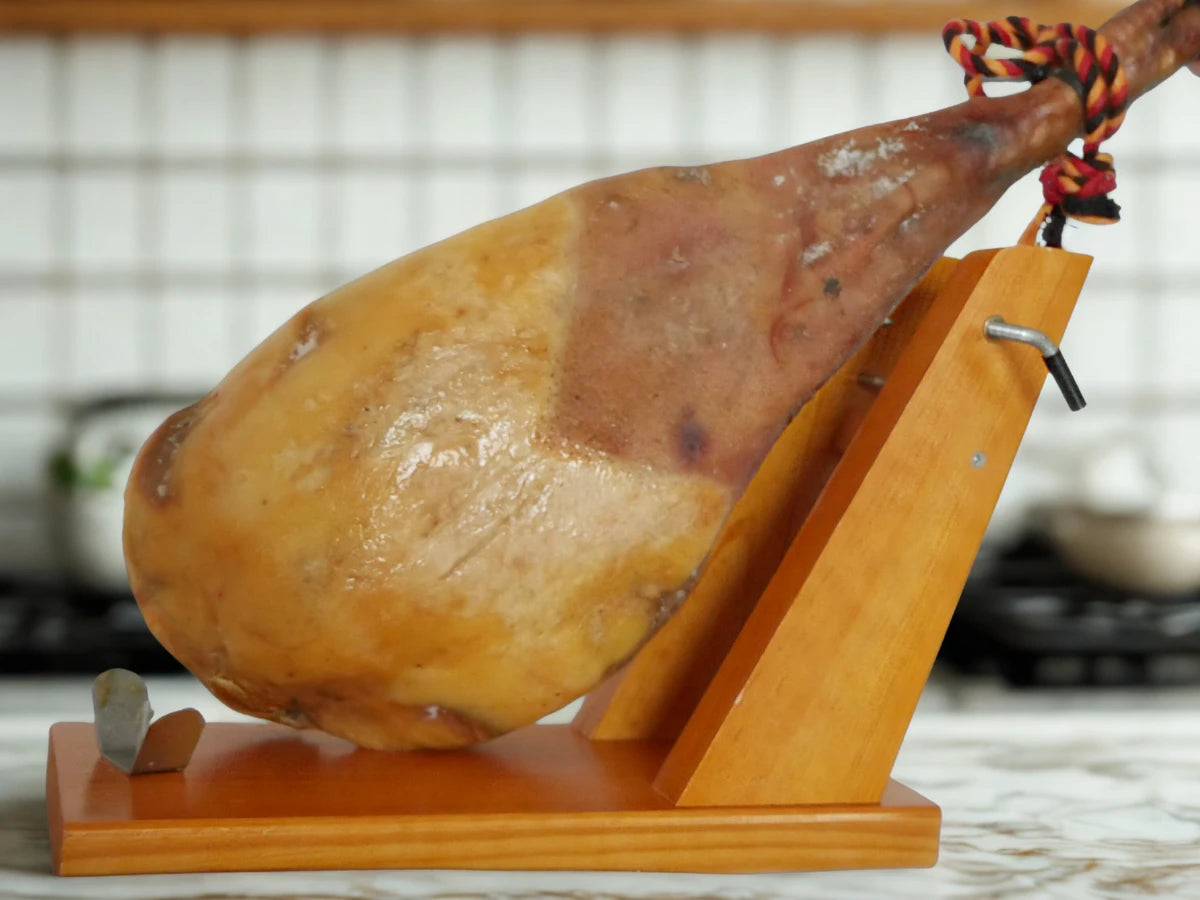 Ganzer Jamón Ibérico Pata Negra auf einem Holz-Schinkenhalter in einer Küche, bereit zum Schneiden.