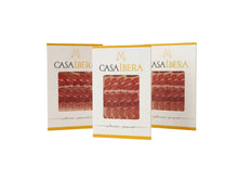 Drei elegante Packungen à 100 g handgeschnittenen Jamon de Bellota Iberico von Casa Ibera, 36 Monate traditionell gereift, vakuumverpackt, freigestellt auf weissem Hintergrund.