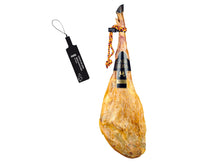 Produktbild eines exklusiven Jamon de Bellota 100 Prozent Iberico Pata Negra von Casa Ibera vor weissem Hintergrund. Der Premium-Schinken zeichnet sich durch seine schlanke Form, die typische schwarze Klaue und eine schwarz-rot-gelbe Kordel aus. Das elegante schwarze Etikett unterstreicht die Spitzenqualitaet. Links ist die gesetzlich vorgeschriebene schwarze Plombe abgebildet, das offizielle Siegel fuer reinen Iberico Bellota Schinken.