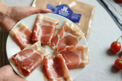 Jamón de Trevélez D.O.P. Serrano Schinken in Scheiben auf Teller serviert, Packung im Hintergrund 