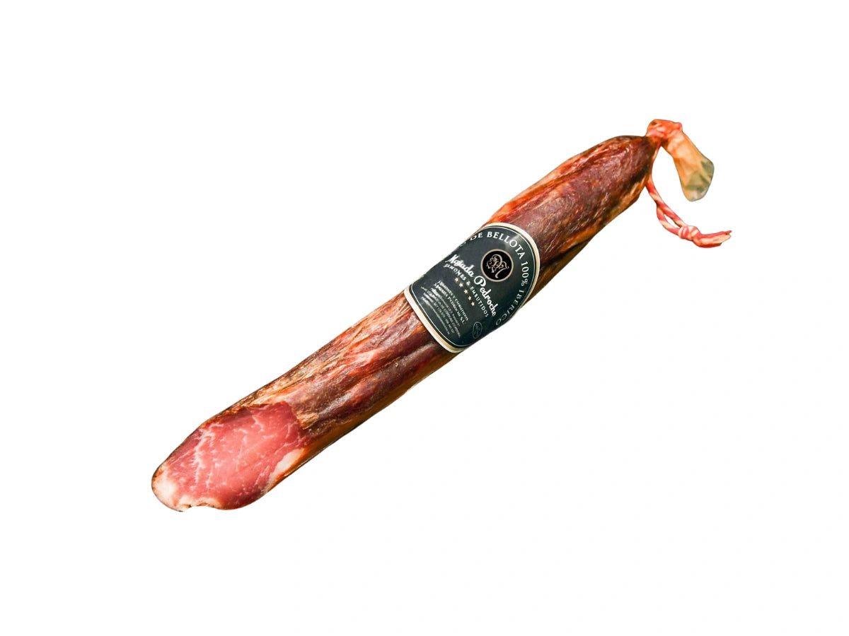 Ganze Stange Lomo Ibérico de Bellota von Majada Pedroche, gewonnen aus dem edlen Lendenstück des iberischen Schweins aus Eichelmast. Traditionell mit Gewürzen mariniert und luftgetrocknet, vakuumverpackt für höchsten Genuss und Aromaerhalt, freigestellt auf weißem Hintergrund.