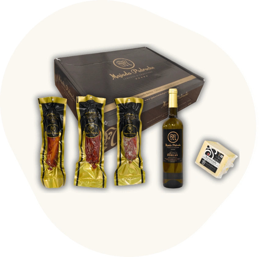 Majada Pedroche Degustationsbox mit ganzen Stücken Chorizo, Lomo und Salami Ibérico, dazu Weißwein und Käse – handwerkliche Feinkost aus Andalusien.