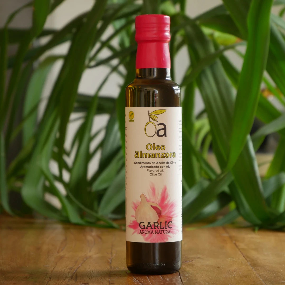 Flasche aromatisiertes Olivenoel mit Knoblauch auf Holztisch vor Pflanzenhintergrund