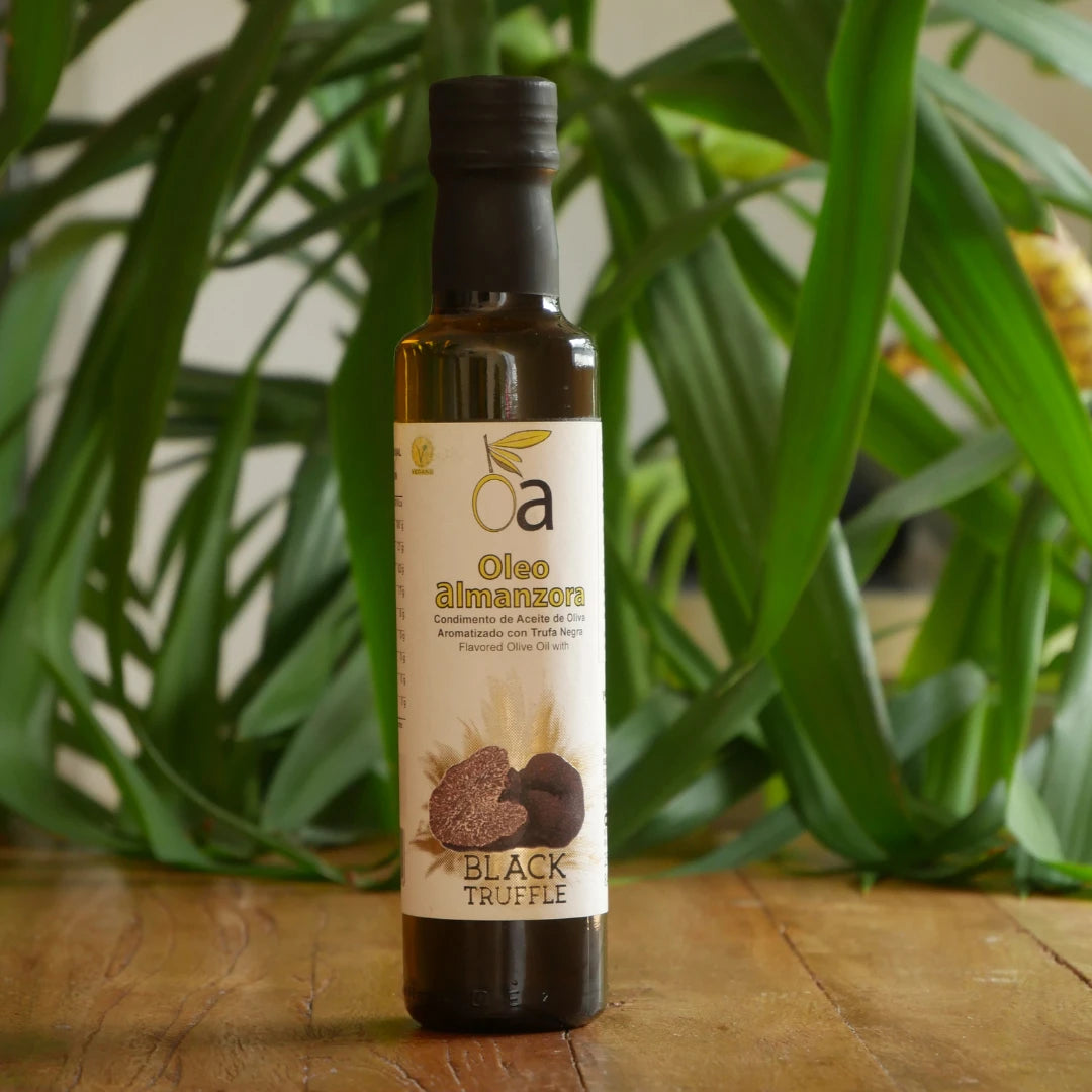 Flasche aromatisiertes Olivenoel mit schwarzem Trueffel auf Holztisch mit gruenem Hintergrund