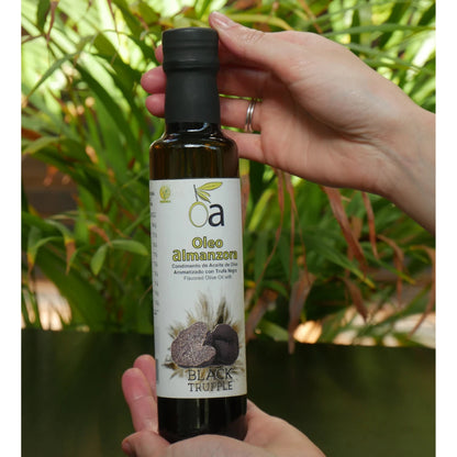 Flasche mit Trueffel aromatisiertem Olivenoel wird in der Hand gehalten, natuerlicher Hintergrund mit Pflanzen