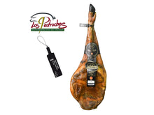 Produktbild einer edlen Paleta de Bellota 100 Prozent Iberica Pata Negra von Majada Pedroche auf weissem Grund. Die 100 Prozent reine Iberico Vorderschulter ist mit dem Herkunftslogo DO Los Pedroches oben links versehen. Das edle Stueck zeichnet sich durch seine charakteristische Form, die schwarze Klaue und hochwertige Etikettierungen aus. Links daneben wird das gesetzlich vorgeschriebene schwarze Kunststoffsiegel fuer hoechste Bellota-Qualitaet gezeigt.