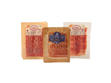 Probierset mit drei verschiedenen Jamon Serrano Sorten, geschnitten und vakuumverpackt (je 100 g), bestehend aus unterschiedlichen Reifegraden von 14 bis 24 Monaten von Jamones Baza und Jamones Juviles, freigestellt auf weissem Hintergrund.