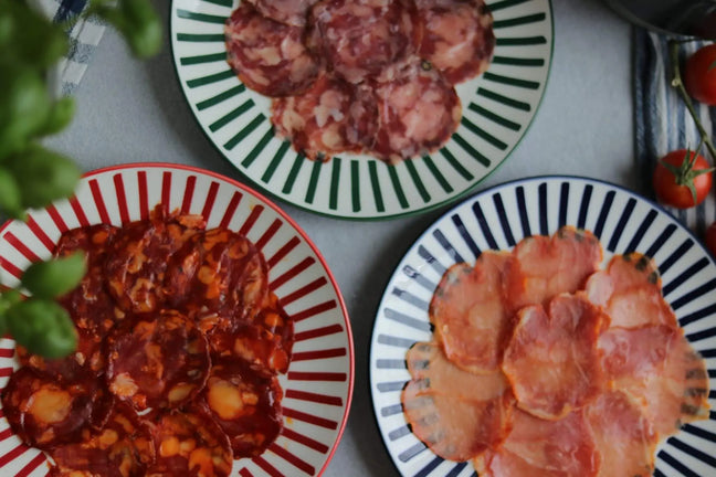Spanisches Wurstset mit Chorizo, Schweinelende und Salami auf bunten Tellern