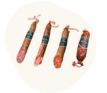 Vier iberische Wurstsorten von Majada Pedroche – Salami, Schweinelende, Chorizo und Edelnackenfilet - am Stück mit Etikett. Die Delikatessen liegen nebeneinander und zeigen ihre unterschiedliche Farbe