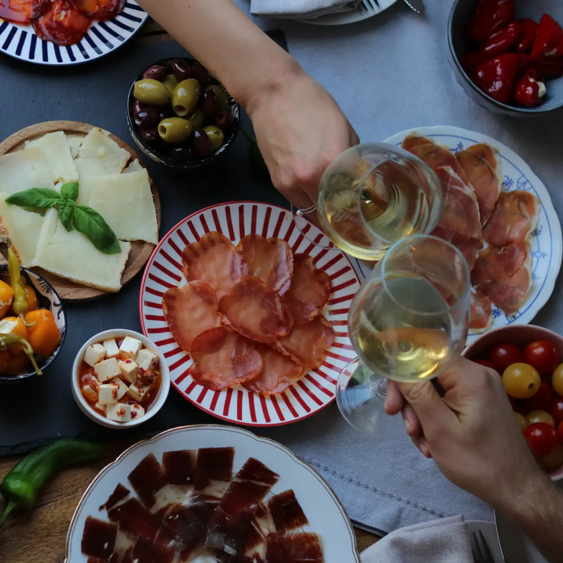 Spanische Tapas-Tafel von oben mit Jamón, Käse, Lomo, Oliven, Paprika und Weißwein – Lifestyle-Banner für spanische Firmengeschenke von La Tradición