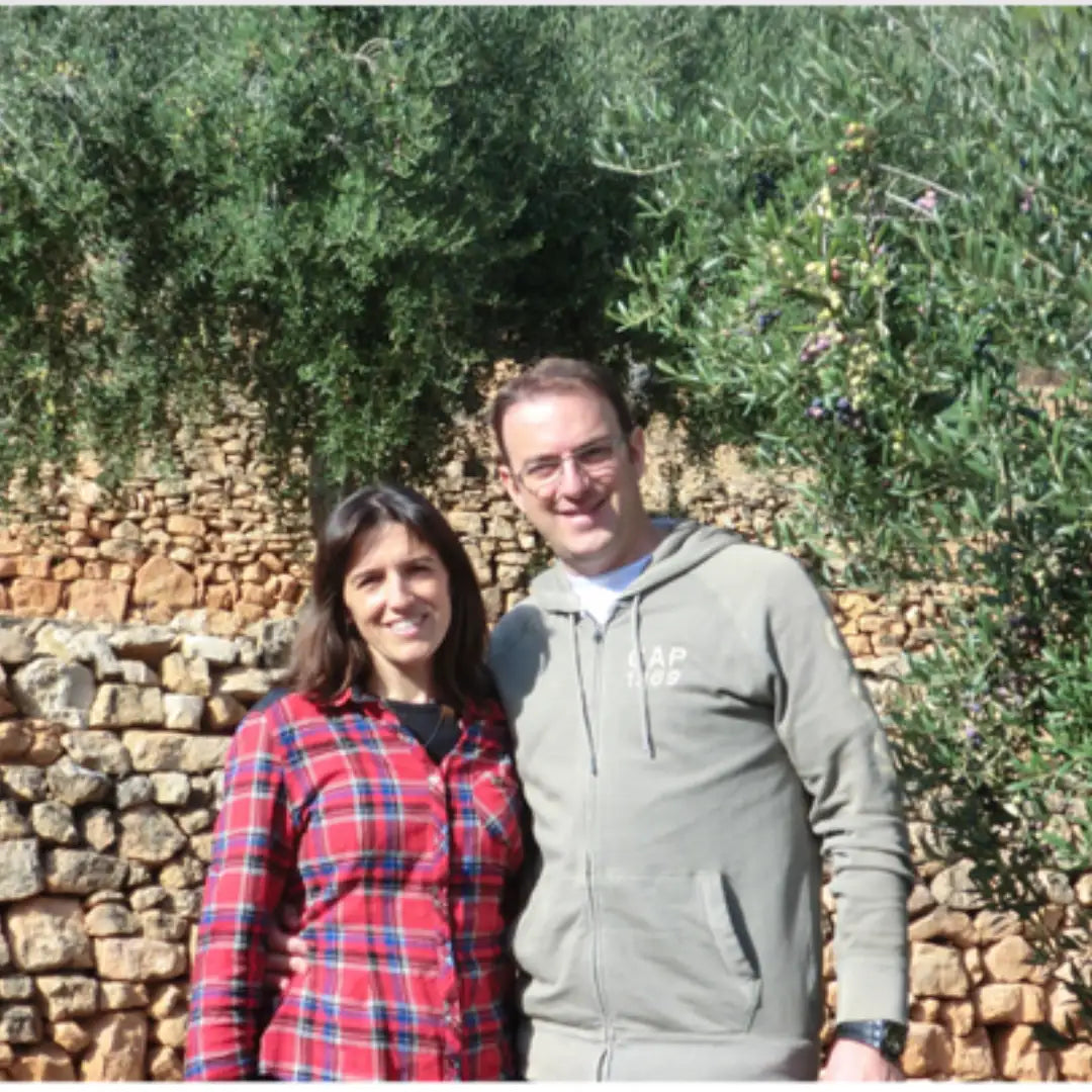 Anna und ihr Mann, Gründer von Priorat Natur, vor Olivenbäumen und einer Steinmauer in Falset, Priorat, Katalonien