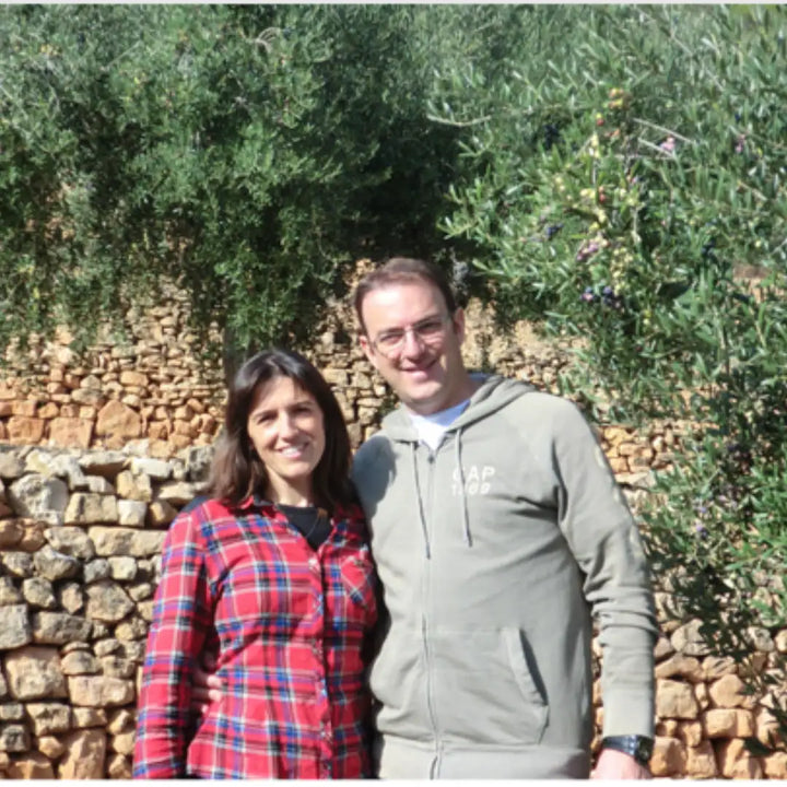 Anna und ihr Mann, Gründer von Priorat Natur, vor Olivenbäumen und einer Steinmauer in Falset, Priorat, Katalonien