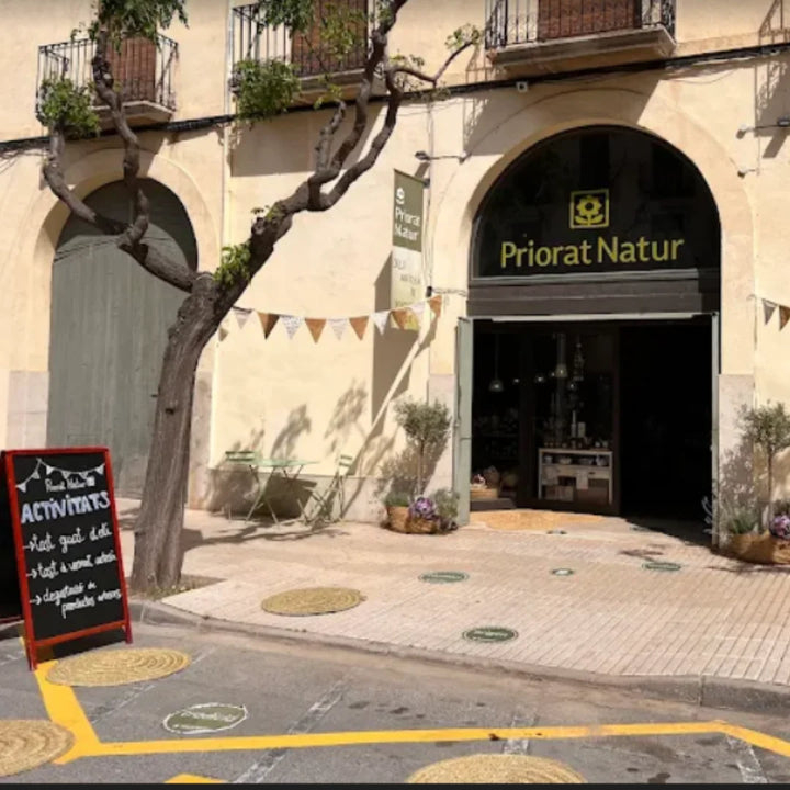 Ladengeschäft von Priorat Natur in Falset, Priorat – Eingang mit Kreideaufschrift, Olivenpflanzen und charakteristischem Logoschild an der Fassade